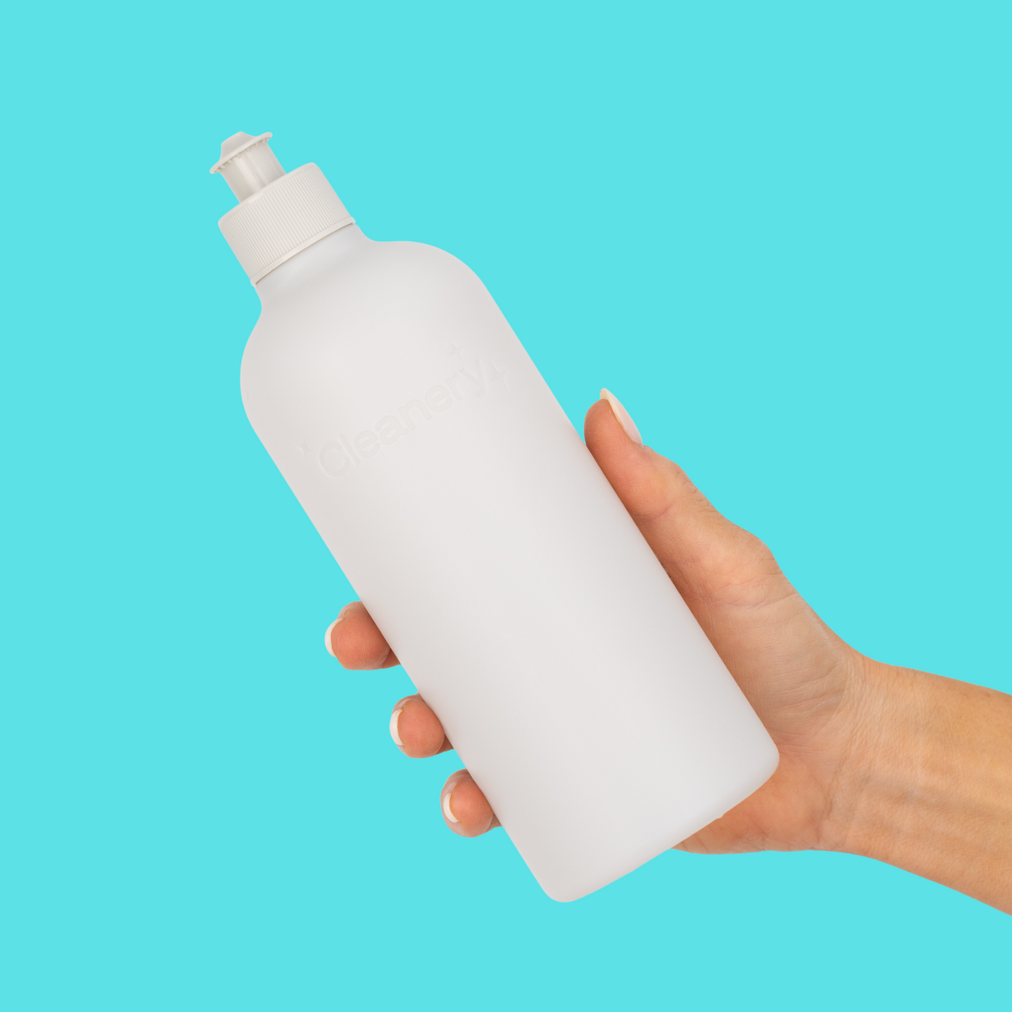 Hand holding a white Cleanery resuable dish washing liquid bottle against a blue background