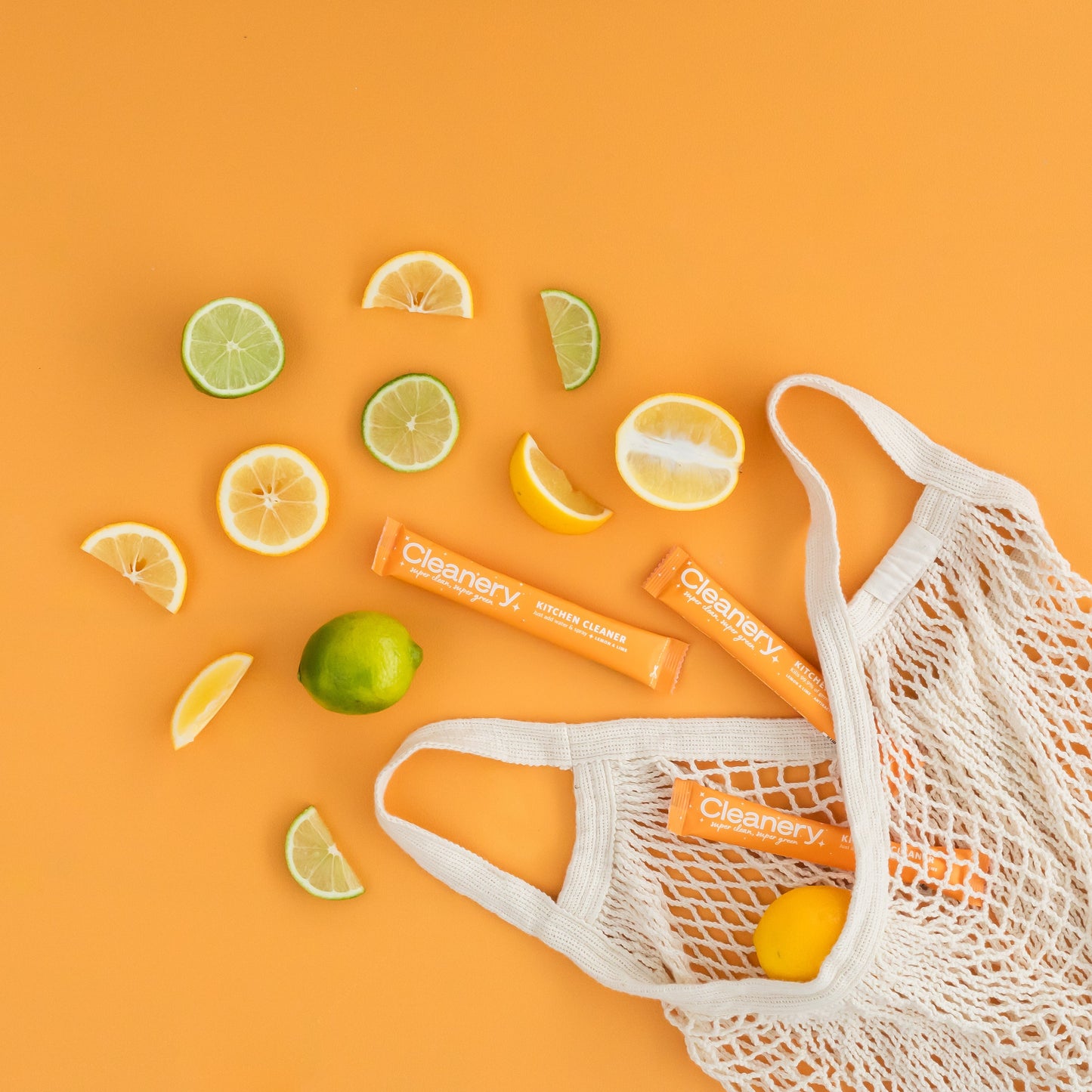 White mesh bag with Cleanery refills on an orange background