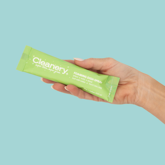 Hand holding Cleanery foaming dish spray refill against blue background