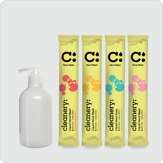 A set of four yellow single-use liquid hand wash sachets with colorful bubble graphics and a white pump bottle of hand wash, arranged on a light gray background. The brand name 'cleanery:' is visible on the sachets.